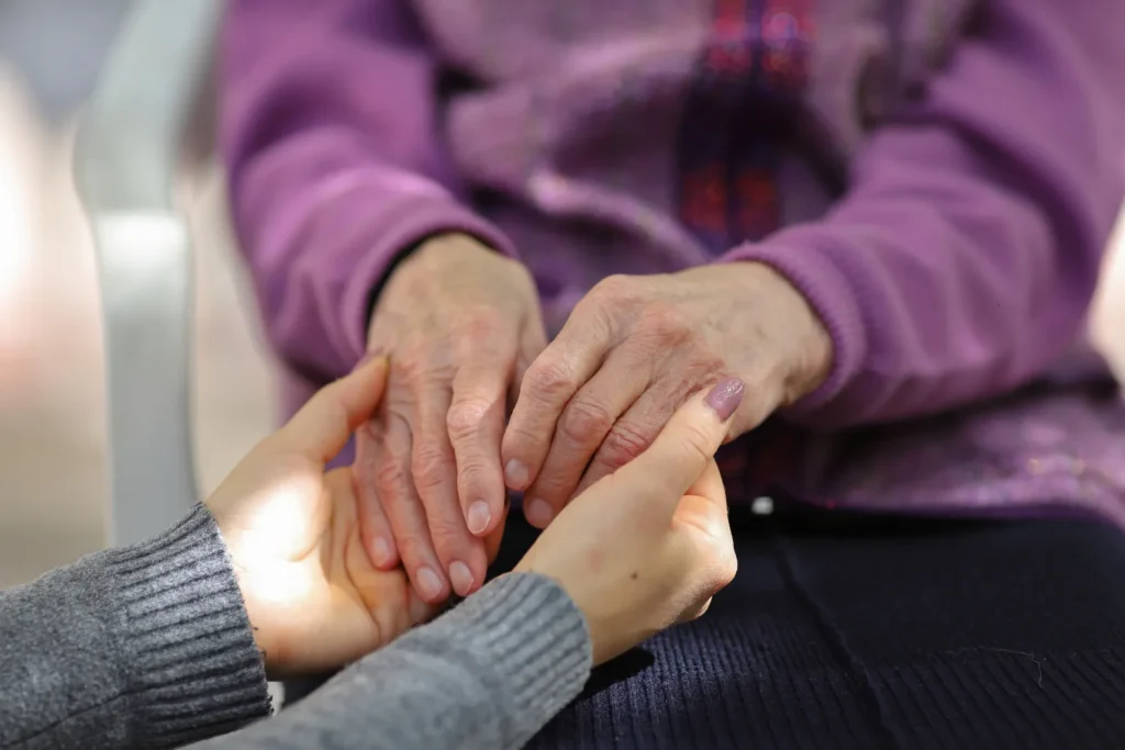 close up of younger and elderly woman holding hands