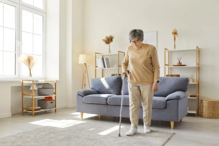 Woman walking with cane in modern living room